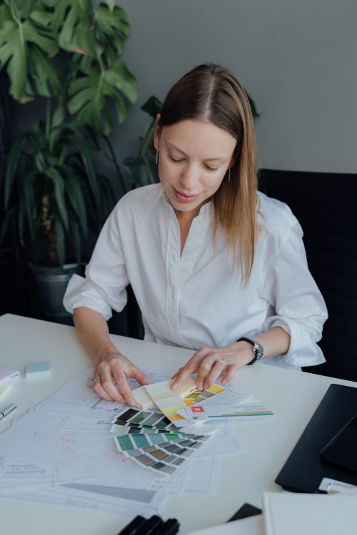 Free Professional interior designer examining color swatches at desk with plant background, focused and concentrated. Stock Photo