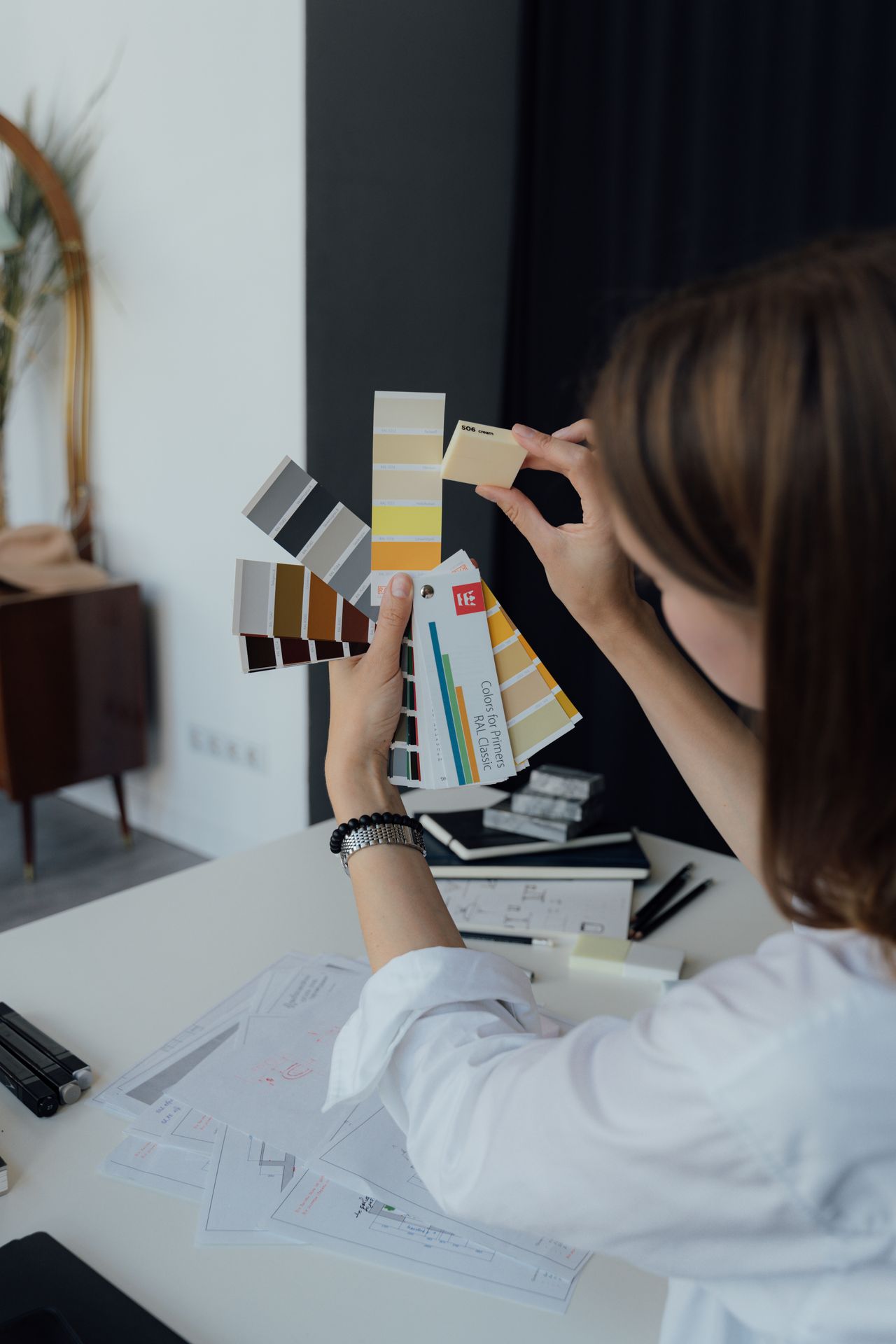 Professional interior designer examining color sample swatches at a workspace desk