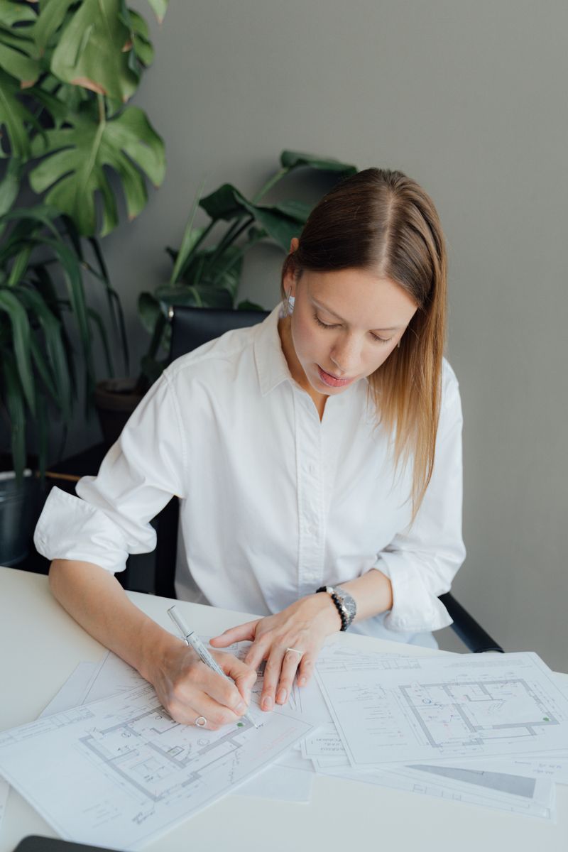 Elena Marchetti — co-founder, reviewing architectural plans at her desk