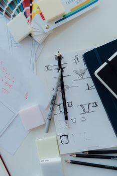 A creative workspace featuring sketches, color swatches, and design tools on a desk.