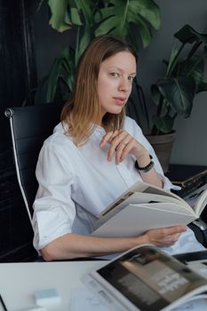 在明亮的办公室里，一位自信的女性正在阅读杂志，非常适合商业和生活方式主题