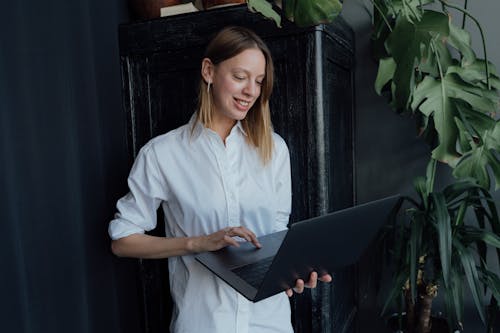 Free Woman in White Button Up Shirt Using Black Laptop Computer Stock Photo