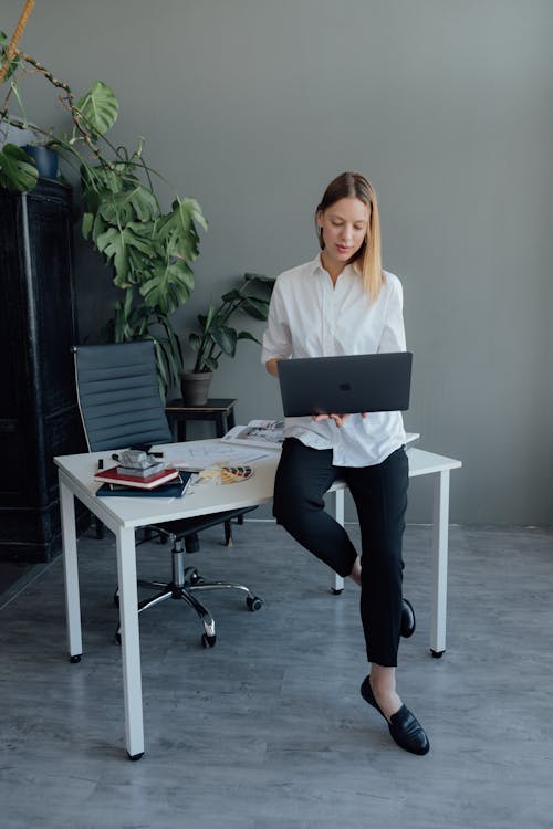 Woman using a MacBook while Sitting on a Desk