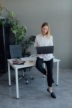 Elegant professional woman in home office using a laptop, embracing a modern remote working lifestyle.