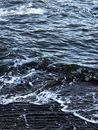 From above of small foamy waves and ripples of dark reservoir in daylight