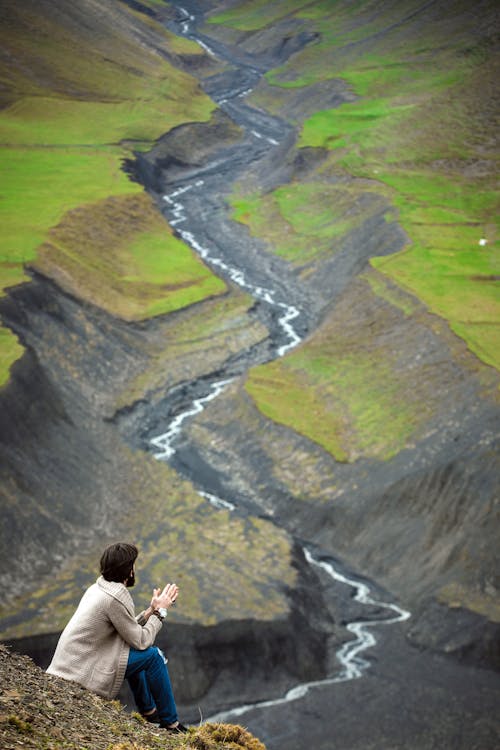 Man in Beige Cardigan Sitting on a Cliff