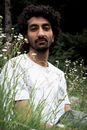 Man in White and Green Crew Neck Shirt Standing Near Green Plants