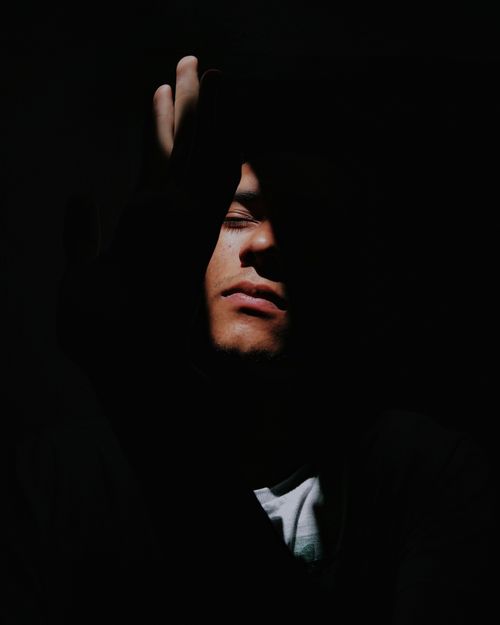 Free Dramatic portrait of a man with eyes closed, obscured by shadows, evoking introspection. Stock Photo