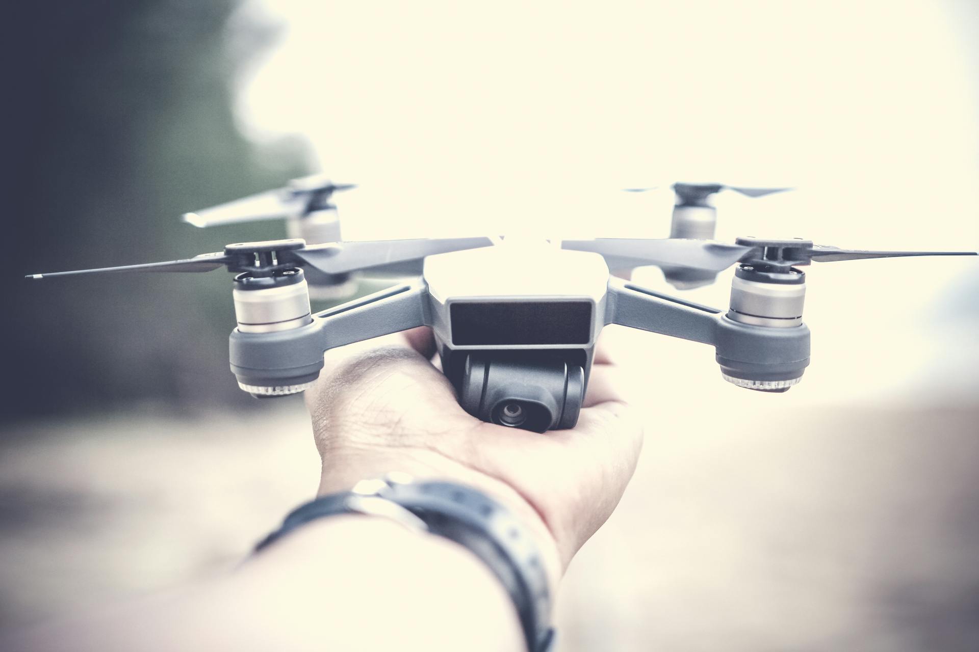 A close-up shot of a person holding a modern drone outdoors, showcasing its design and technology.