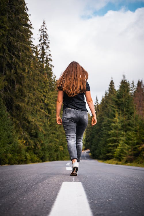 Woman Walking on an Asphalt Forest Road