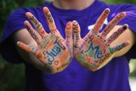 Person in Purple Crew Neck T Shirt With Just Me Painting on Hand