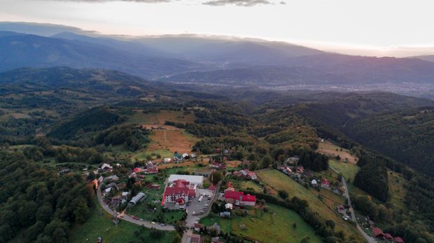 Aerial view of Petroșani, Romania showcasing beautiful rolling hills and a small town nestled among lush greenery.