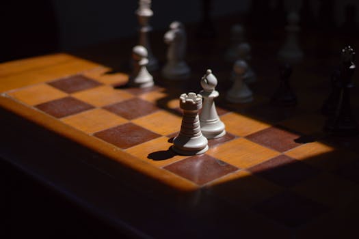 Detailed view of a chess game in progress with shadows on a wooden board
