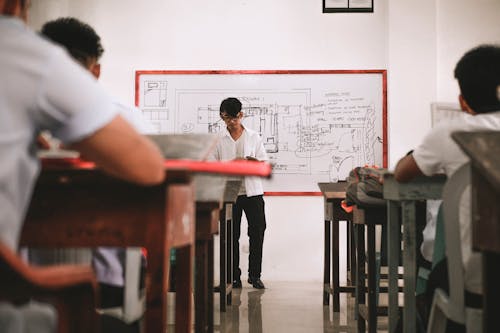 Man in White Shirt Standing Near White Board