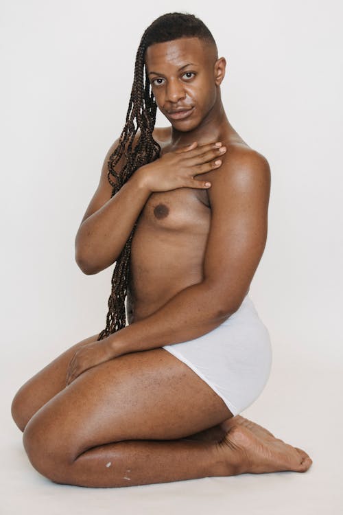 Androgynous black man in white underwear sitting in studio