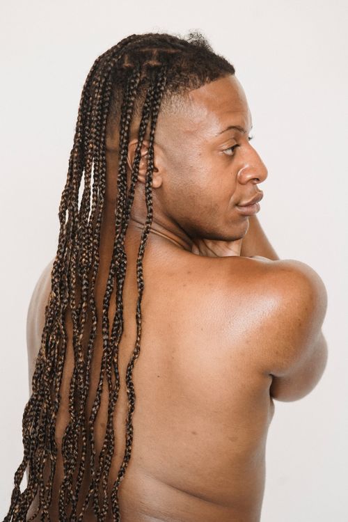 Free Back view of shirtless African American male with Afro braids standing on white background with arms bent in elbows in studio Stock Photo