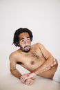 Shirtless black man with spotted skin resting on floor