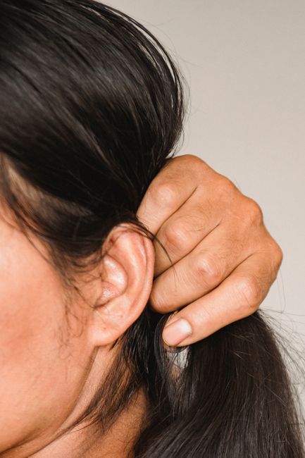Fotomural Acercamiento de una persona ajustando el cabello con enfoque en la mano y la oreja, transmitiendo calma y serenidad.