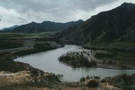 阴天里，平静的河流在绿色山谷和群山的环绕中流动，景色壮观