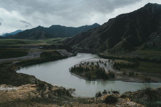 阴天里，平静的河流在绿色山谷和群山的环绕中流动，景色壮观