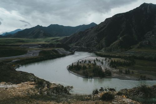 Free Spectacular scenery of calm river flowing among green valley and surrounded by mountains in cloudy day Stock Photo