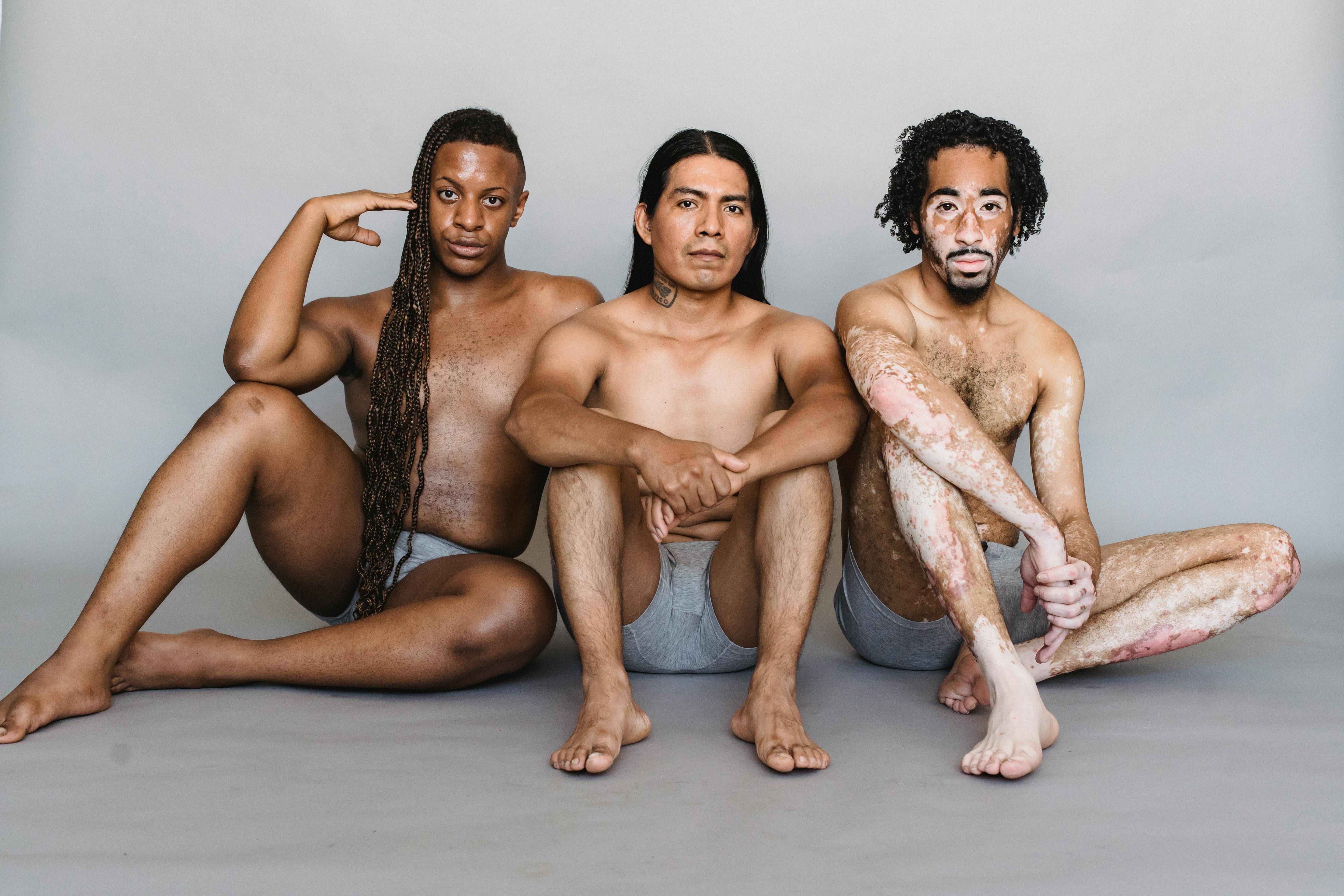 unemotional diverse men in underpants sitting on floor