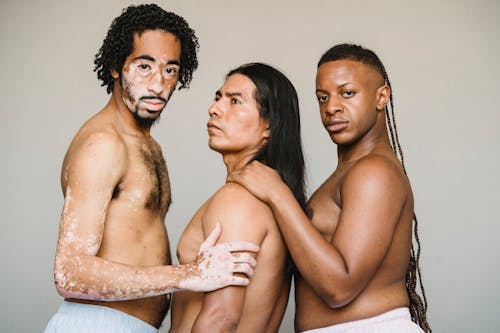 Multiethnic homosexual calm men with naked torso standing in studio