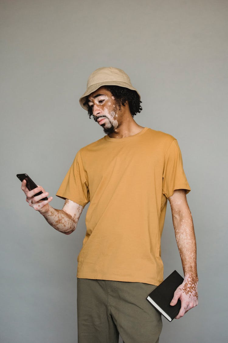 Serious Black Man Browsing Smartphone In Studio