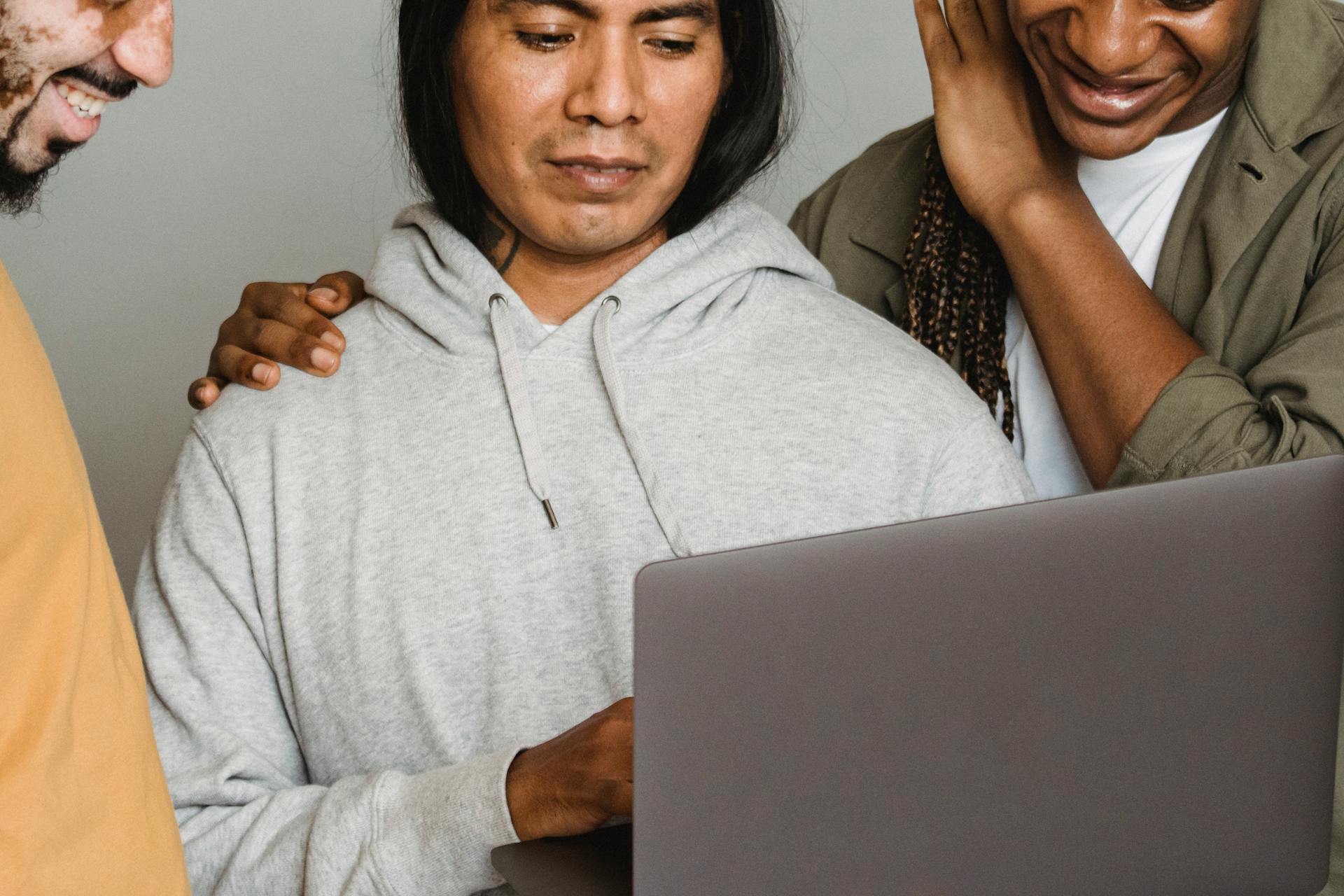 A group of diverse colleagues working together on a laptop, showcasing teamwork and digital collaboration.