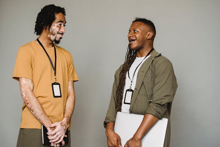 Cheerful Black Androgynous Man Looking At Coworker