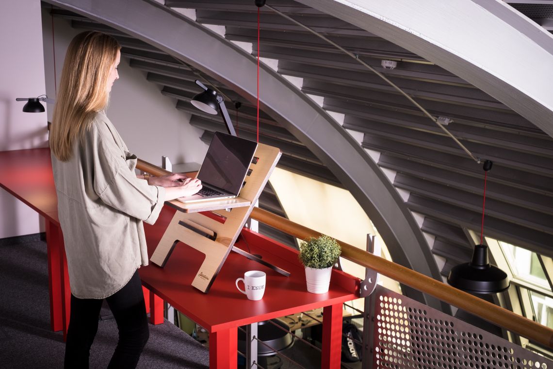 Woman using a laptop at a standing desk in a modern ergonomic workspace