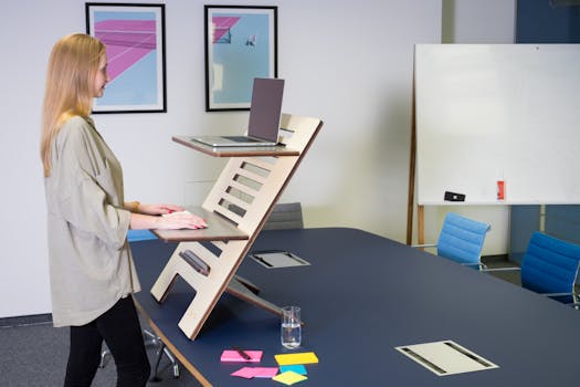 A woman uses an adjustable standing desk in a contemporary Germany office setting.