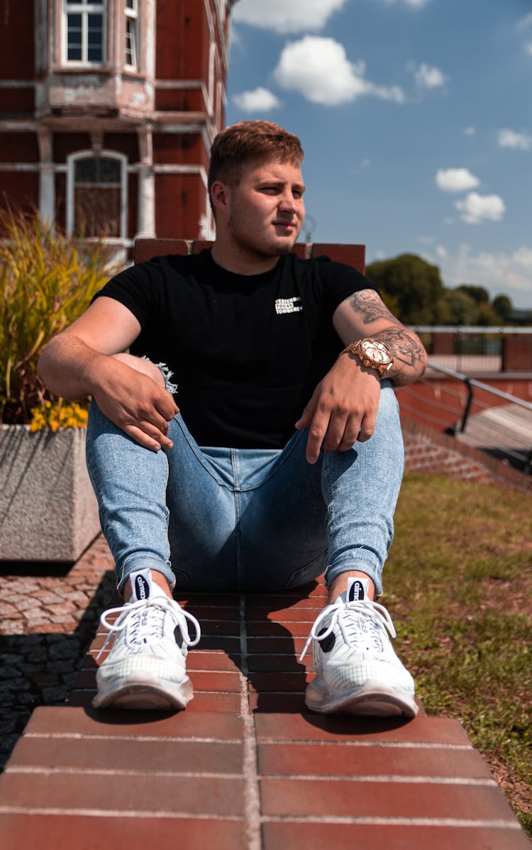 Trendy Tattooed Dreamy Man On Pathway Near Old House