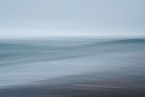 Long-exposure blur of a calm blue-gray sea meeting a pale sky