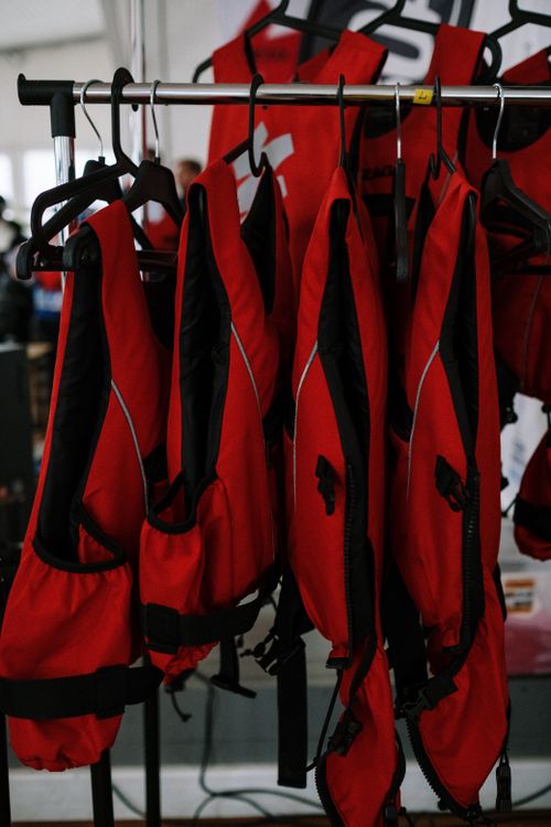Free Red life vests arranged on a clothesline indoors for safety and organization. Stock Photo