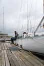 Man in Blue Jacket Sitting on Wooden Dock