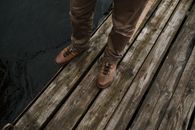 Person in Brown Leather Boots Standing on Brown Wooden Dock