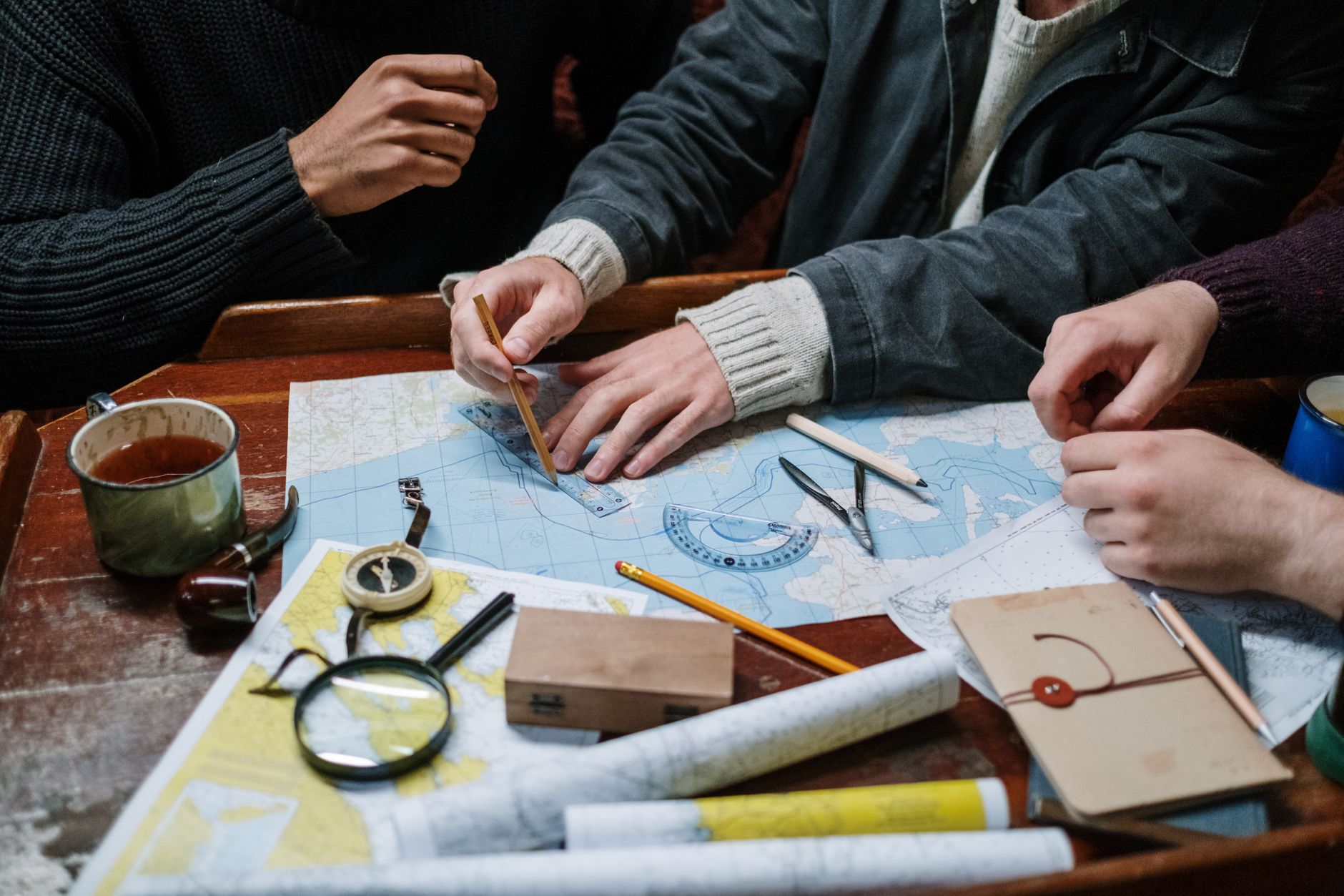 two friendly trip planners leaning over a large paper map of Michigan at a wooden table, pointing at