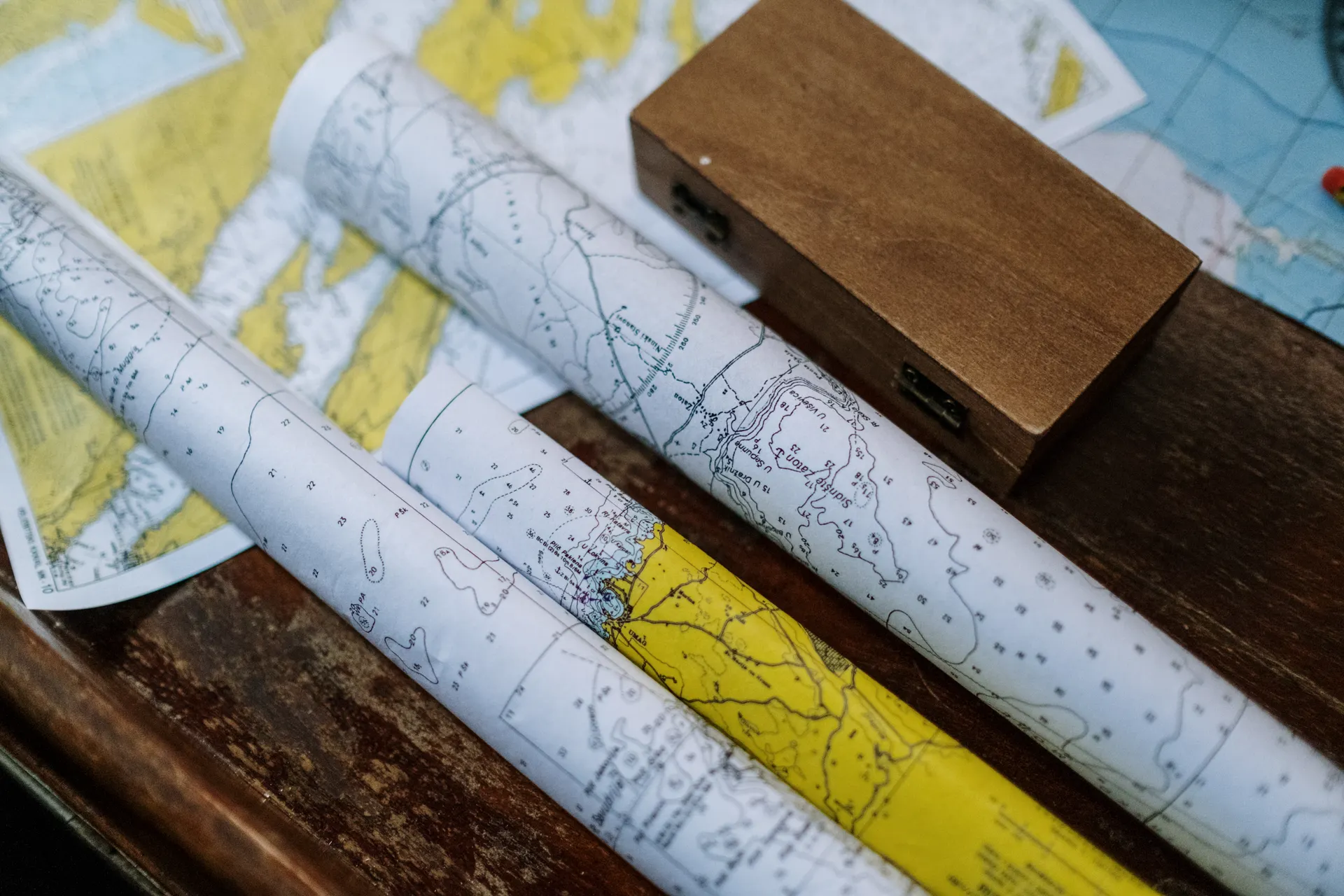 Rolled paper maps on a wooden table during trip planning Rolled paper maps on a wooden table during trip planning