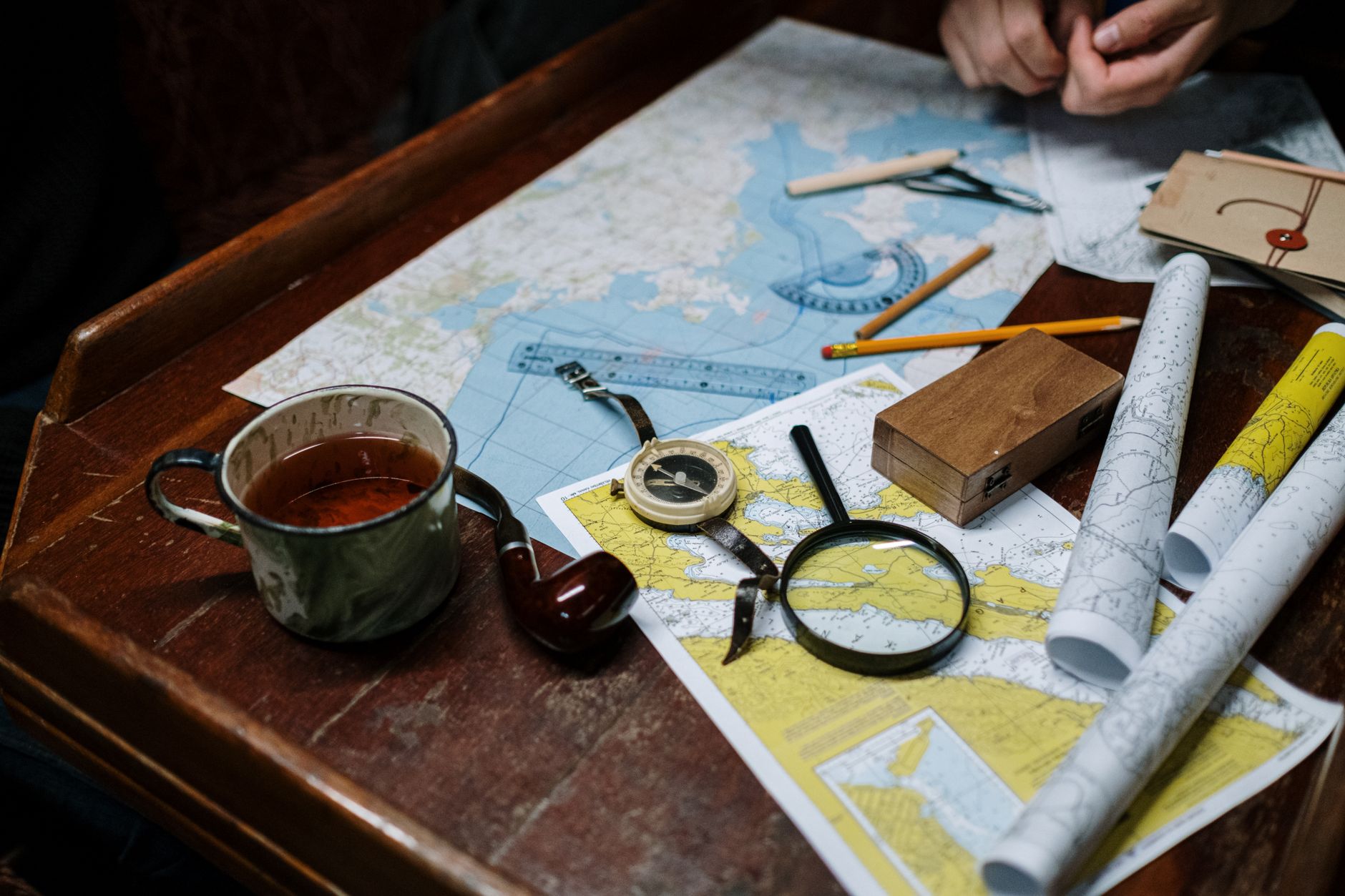 Overhead view of navigation tools with maps, compass, and coffee cup.