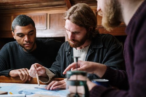 Free A group of young men engaged in planning a nautical adventure indoors using a detailed map. Stock Photo