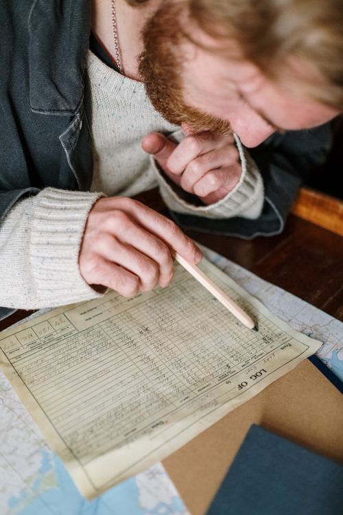Free A man uses a pencil to study and analyze a detailed document. Stock Photo