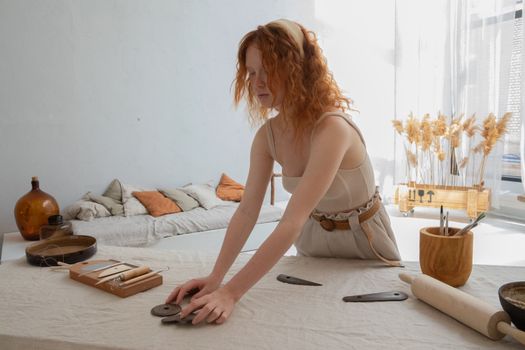 Craftswoman preparing clay equipment on table in light workspace