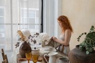 Craftswoman at table with busts and potted plants