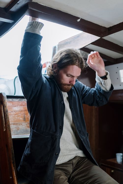 Free Bearded man wearing a blue jacket and sweater indoors, captured in a thoughtful pose. Stock Photo