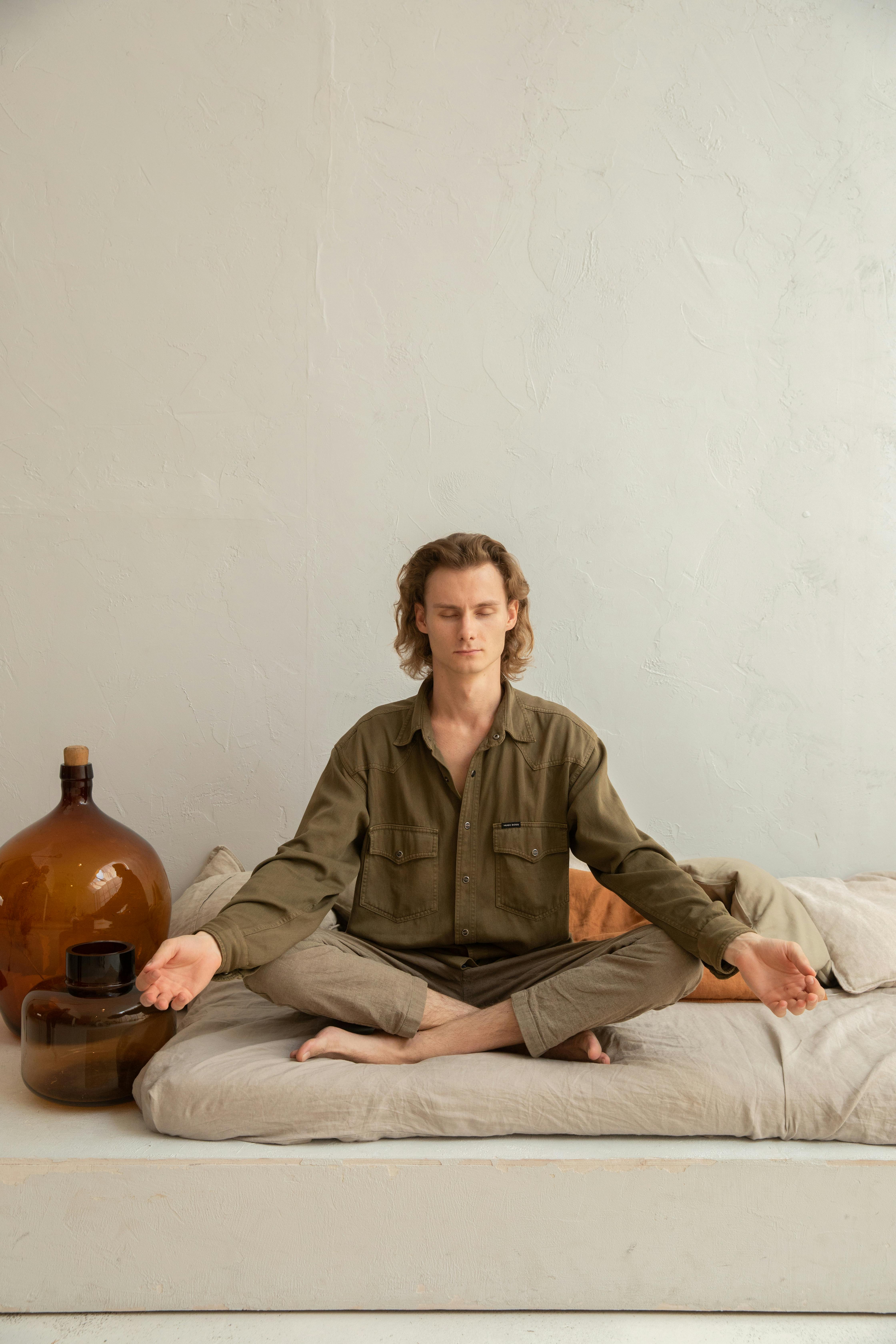 mindful man with crossed legs practicing yoga at home