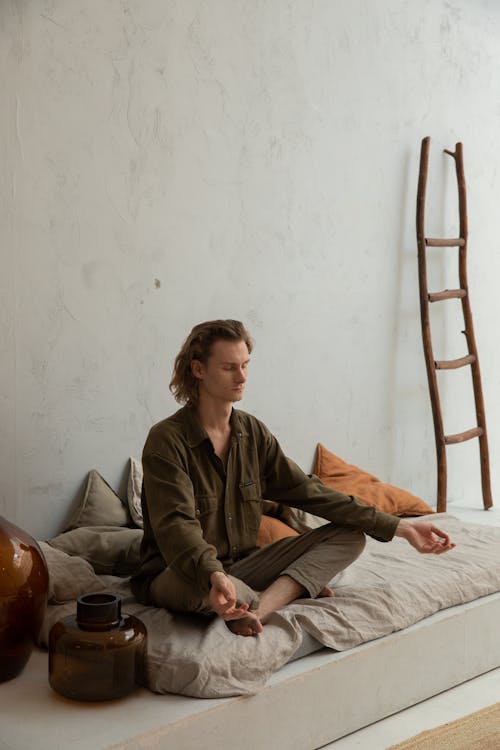 Reflective man practicing yoga in Lotus pose in house