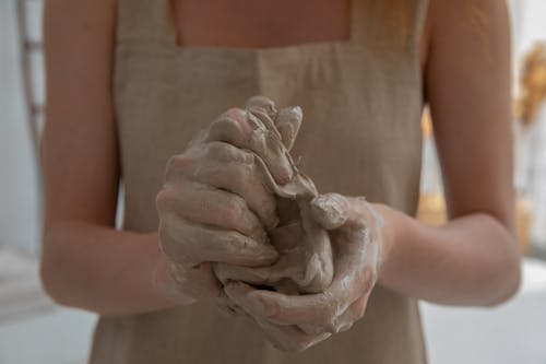 Crop faceless woman kneading clay in workshop