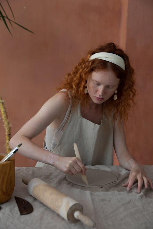 集中在陶器中的女人切割粘土板