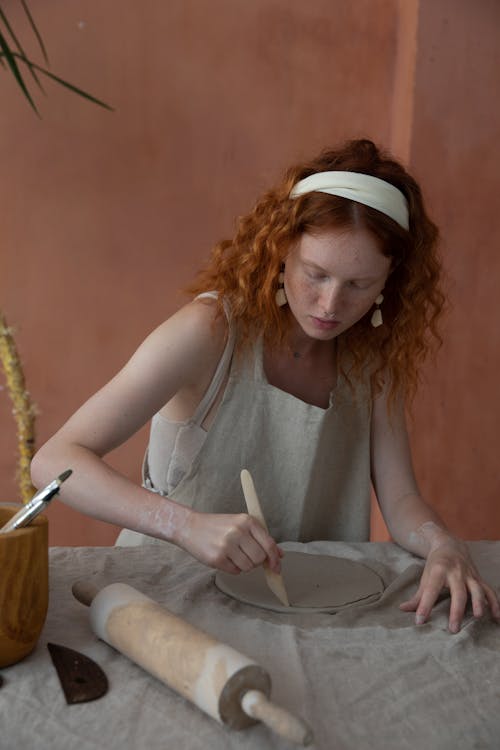 Focused woman cutting clay slab in pottery